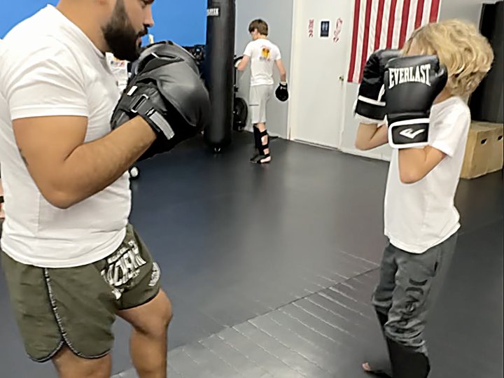 Kru Claudiu holding pads for a young student